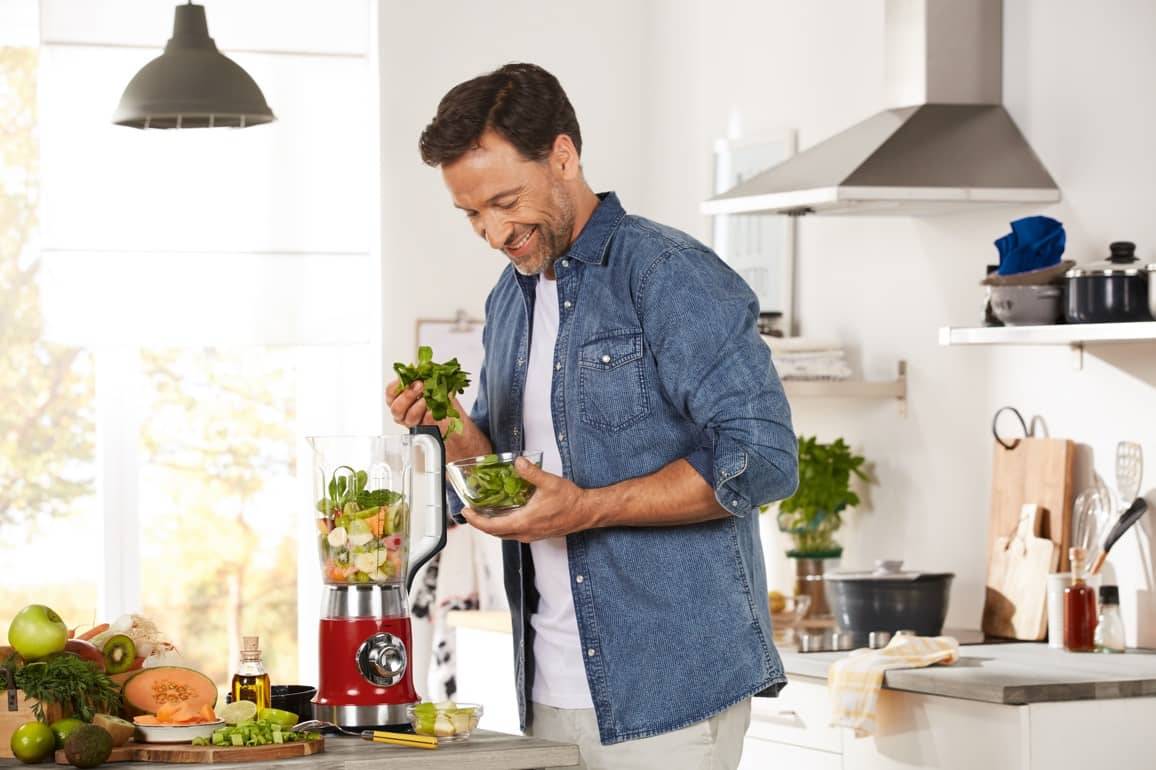 Mann macht Smoothie im Mixer.