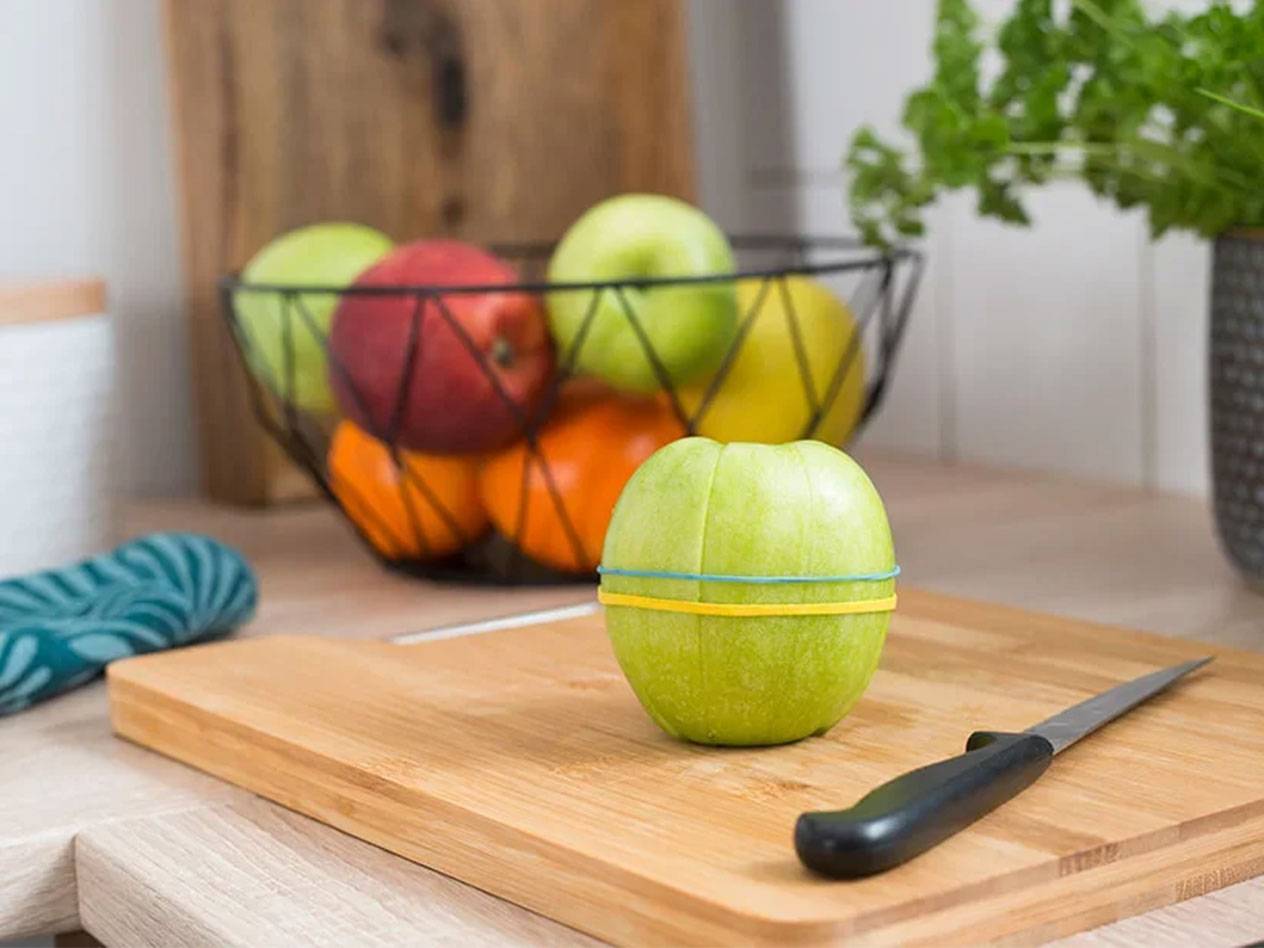 Apfel mit Gummibändern auf einem Holzbrett.